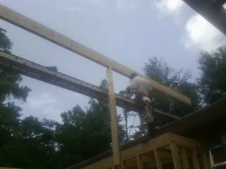 Carpenter setting a ridge beam over a new addition frame — Ice Dam Removal by Roofing Brothers in Pennellville