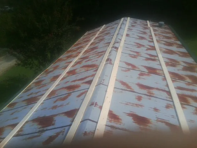 Rusted metal roof panels with new wood purlins before replacement — Storm Damage Roof Repair in Pennellville by Roofing Brothers