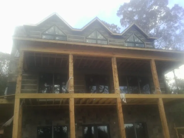 Dormers and porch framing on a large log home under construction — Roof Coating work by our crew in Pennellville