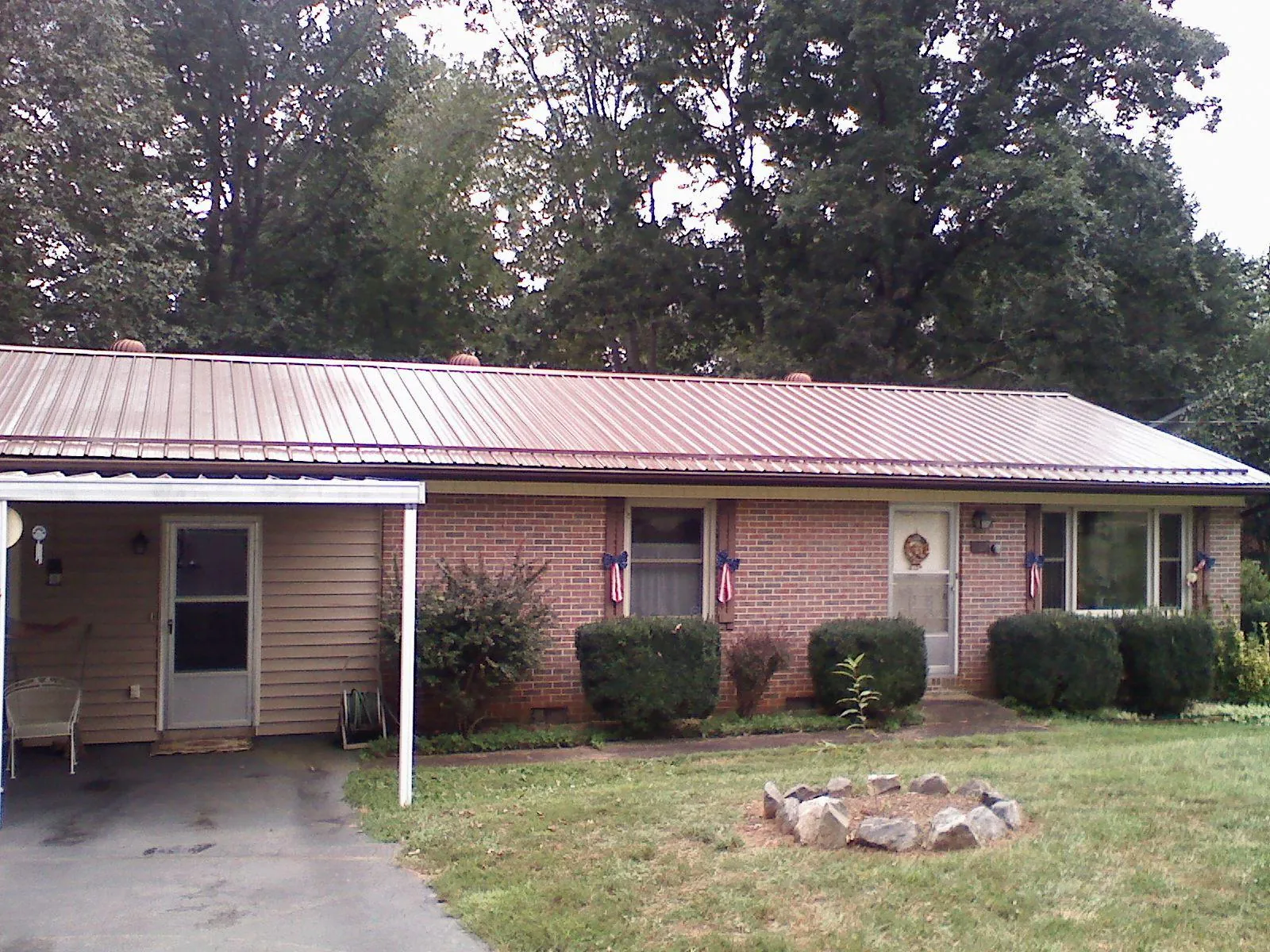 Bronze metal roof and carport on a brick ranch home — Roof Repair work by our crew in Pennellville
