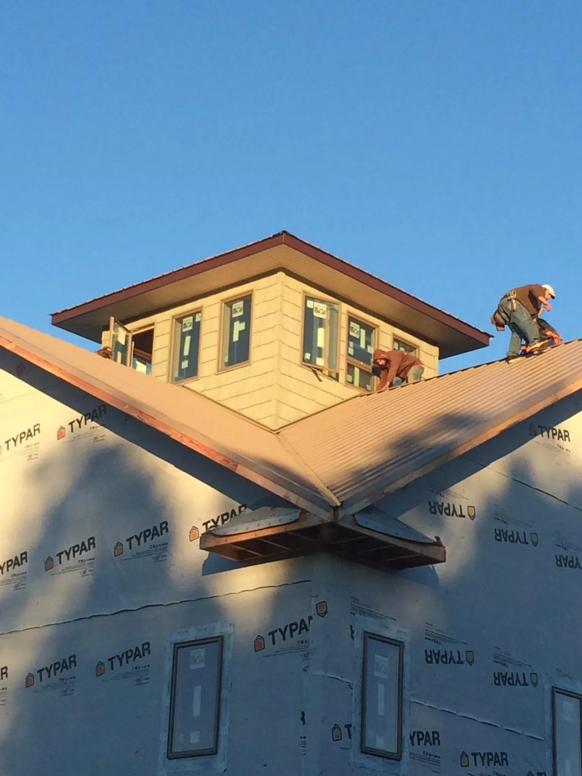 Roofers working around a rooftop cupola on a new metal roof at sunset — Roof Waterproofing in Pennellville by Roofing Brothers